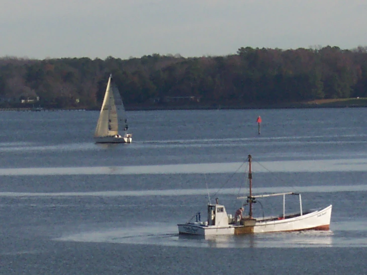 sailboat and small boat floating in lake near shore