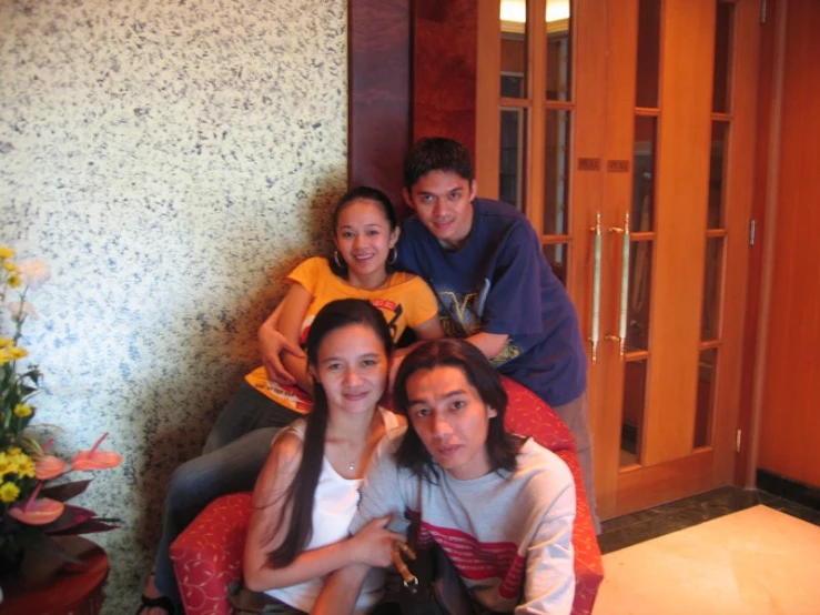 people sitting on a red sofa posing for the camera