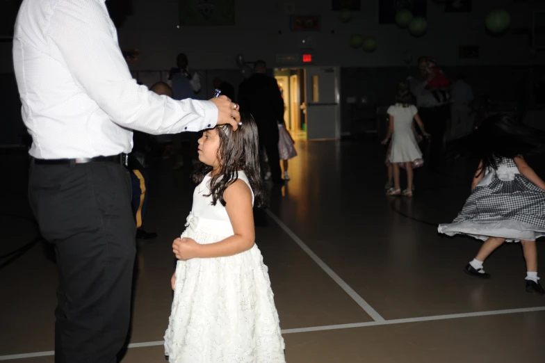 a child watches as the adult gives her flower girl a hair