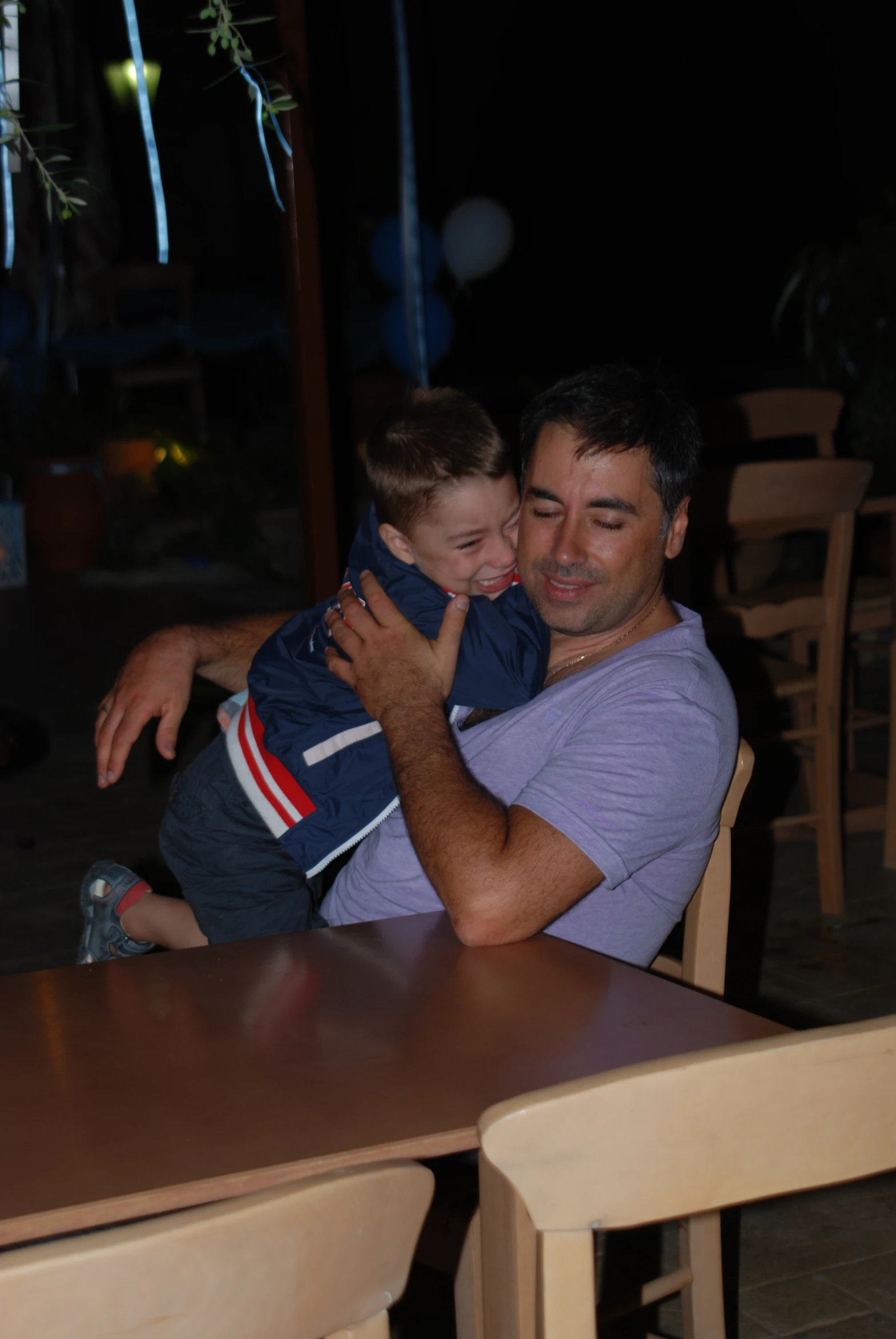 a man sitting at a table holding his son