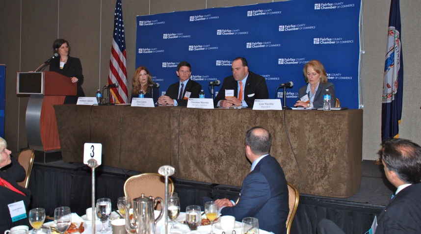 a group of people sitting at a table in front of a blue backdrop