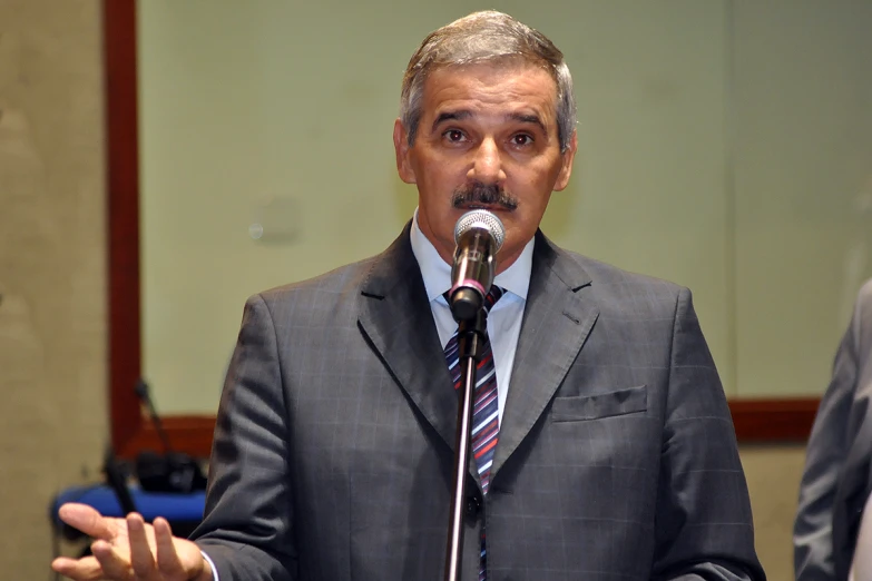 a man wearing a suit standing in front of a microphone