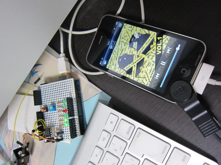 a cellphone hooked up to a white keyboard