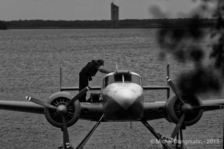 a man standing on the back of an old propeller plane