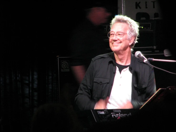 an older man with a black shirt is playing the keyboard
