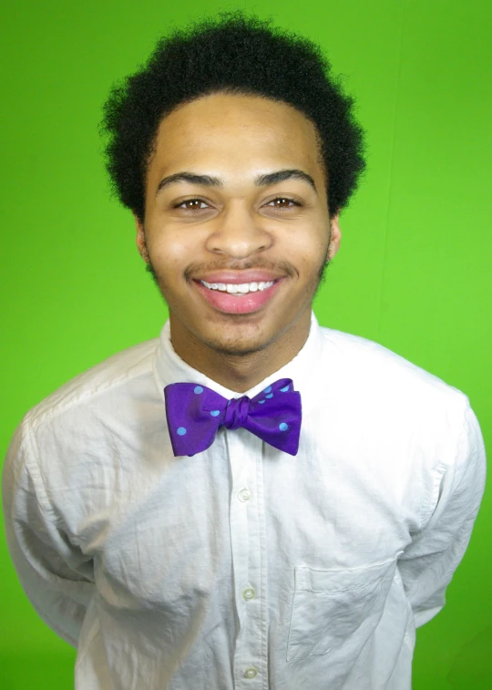 a smiling young man in white shirt and blue bow tie