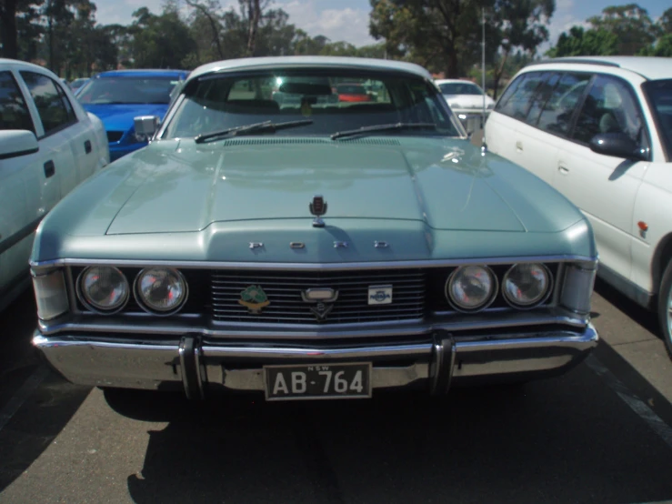 an older model car sits parked amongst other cars