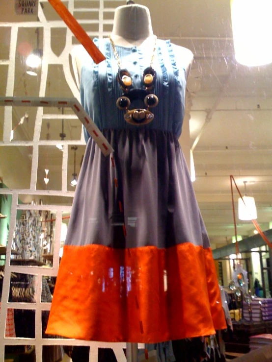an orange and blue dress hangs in a window