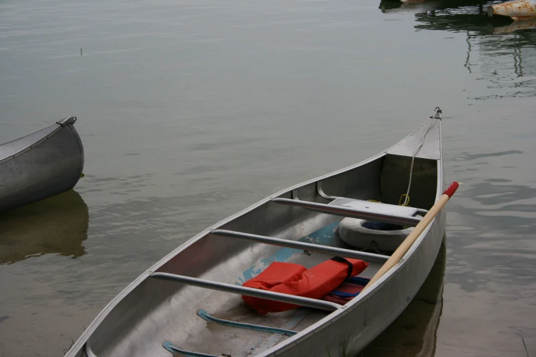 a silver row boat with one oar attached is in the water