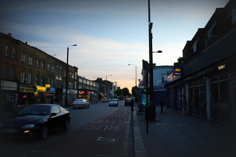 cars are parked on the street next to businesses