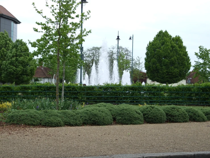 the water fountain is in a park setting with green trees