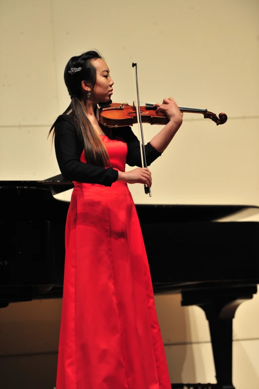 an elegant woman wearing a red dress plays the violin