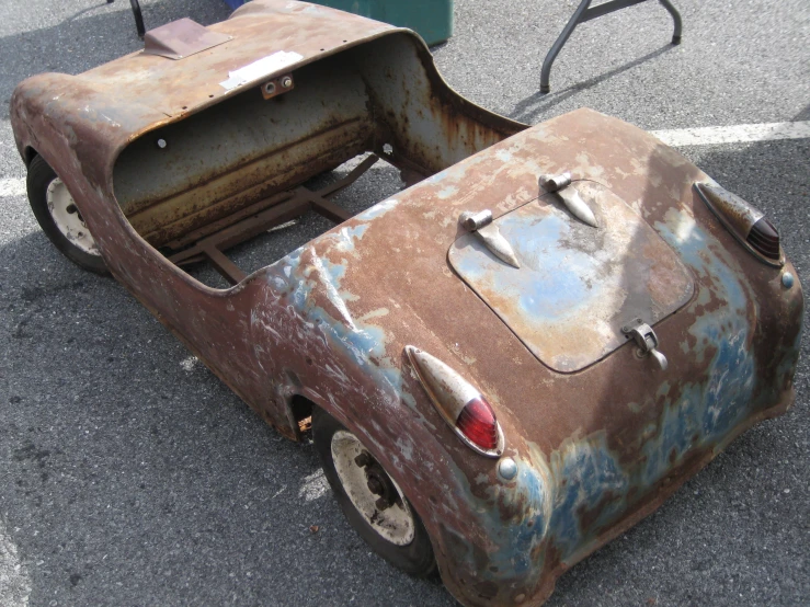 the remains of a rusty old car on the pavement