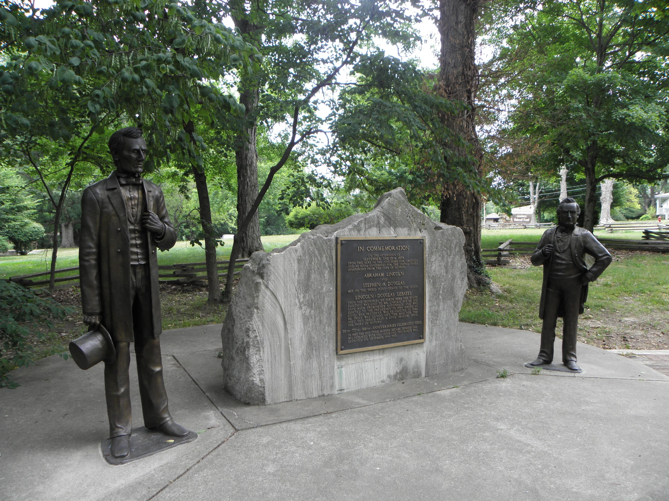 two statues with a hat and suit are sitting in a field