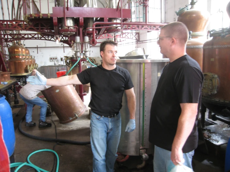 two men with copper buckets in an industrial area