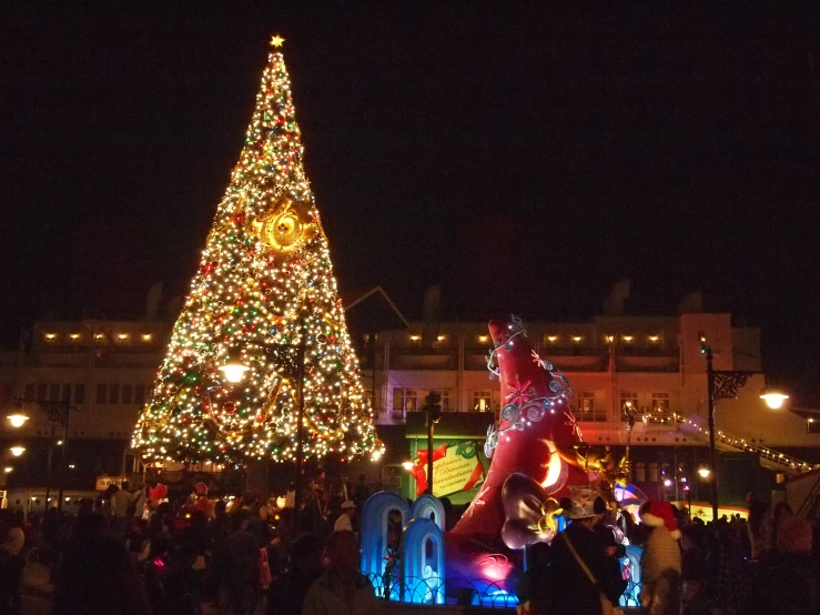 some people standing in front of a giant christmas tree