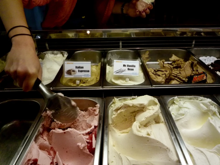 a woman scoops ice cream in a display case
