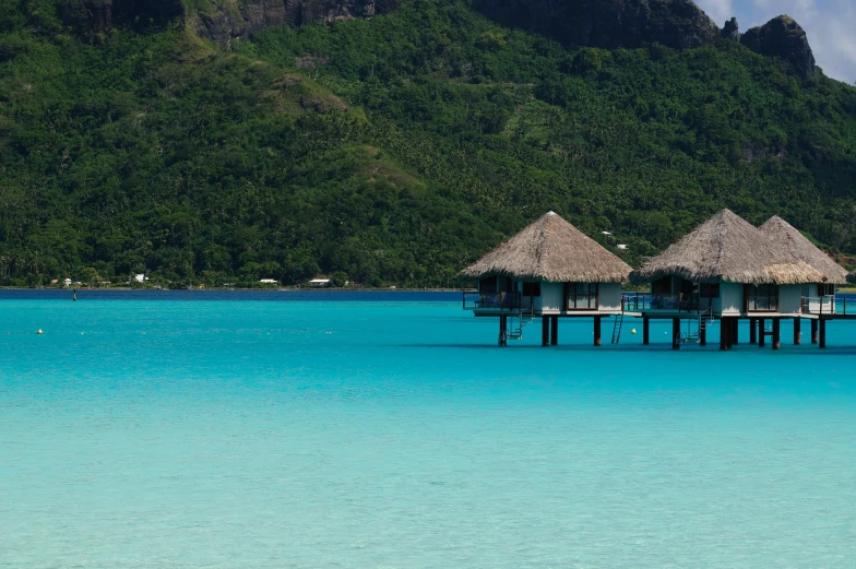 an island with two huts, sitting out over a body of water