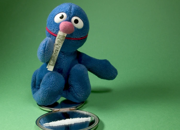a blue stuffed animal with a spoon in his mouth