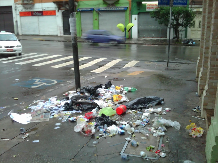 a street with garbage everywhere on it and parked cars