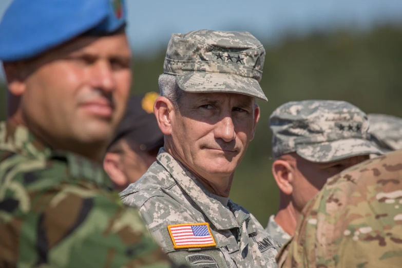 military men in uniform talking together with a man in a blue beret