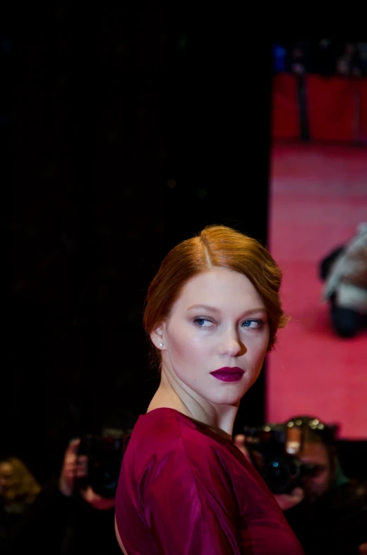 a red haired woman with dark purple lipstick and green eyes