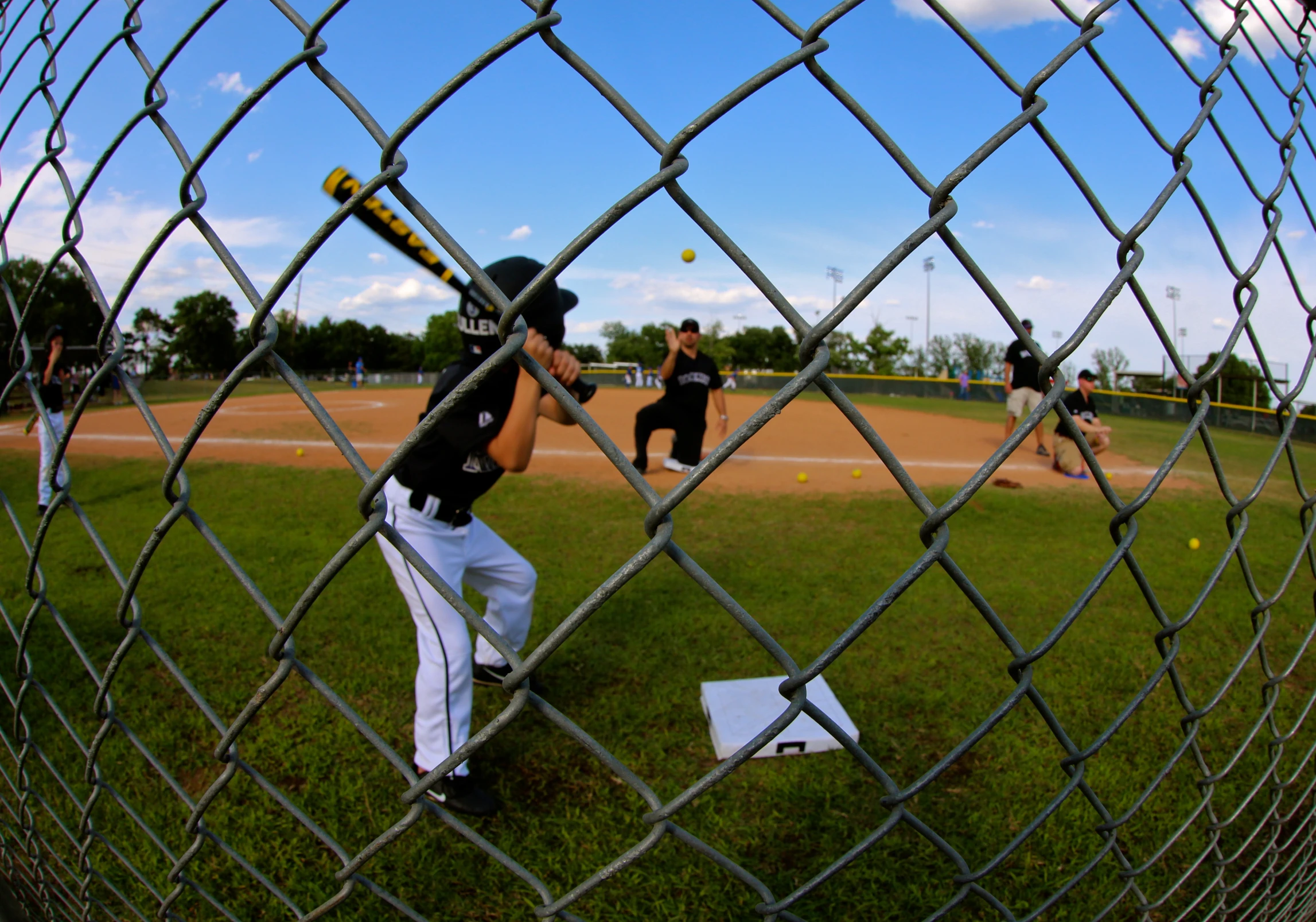 young s practicing baseball inside a chain link fence