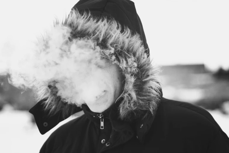 a young man is wearing a jacket with hood and smoking