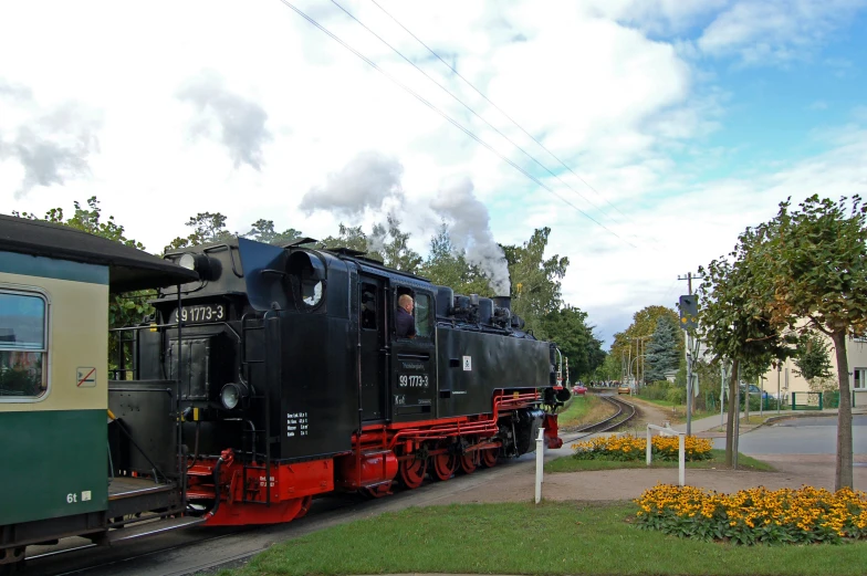 a black train riding past an old colorful building