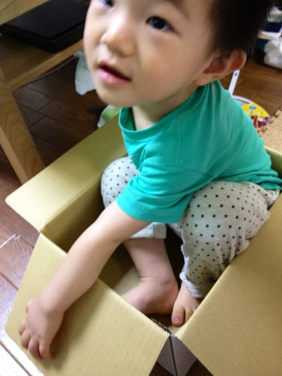 a little boy is sitting in a cardboard box