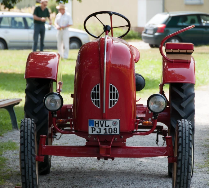 an old fashioned red model t tractor parked on the side of the road