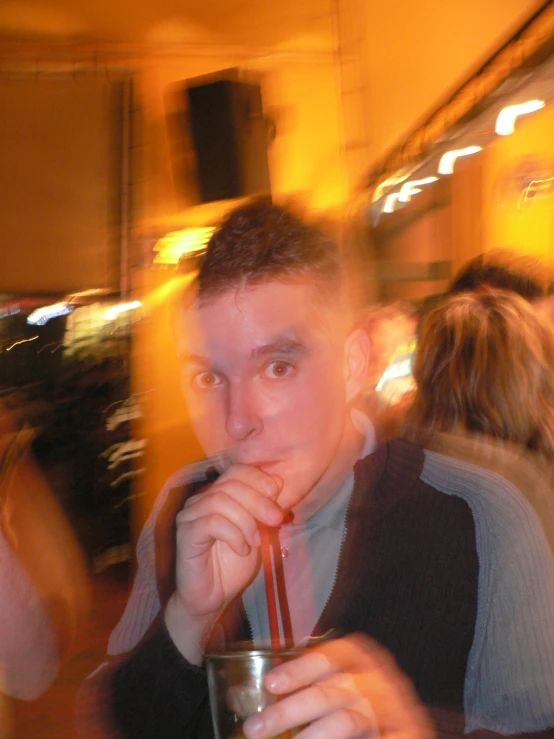 a guy sitting at a table drinking a beverage