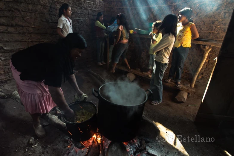 a group of people cooking a meal with boiling pots