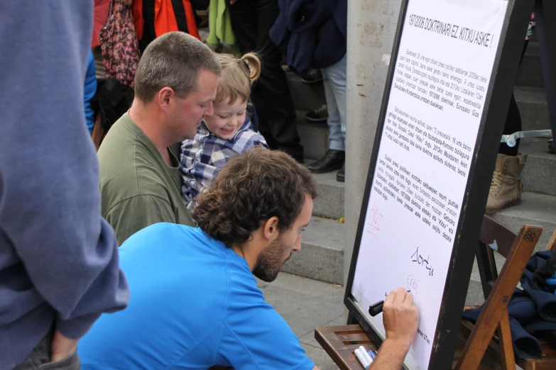 a man writing on a board with his family