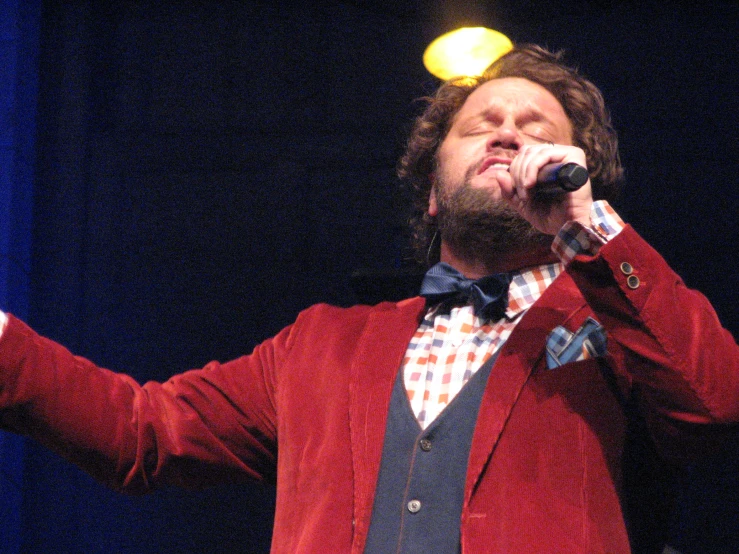 the man is singing into the microphone at a concert