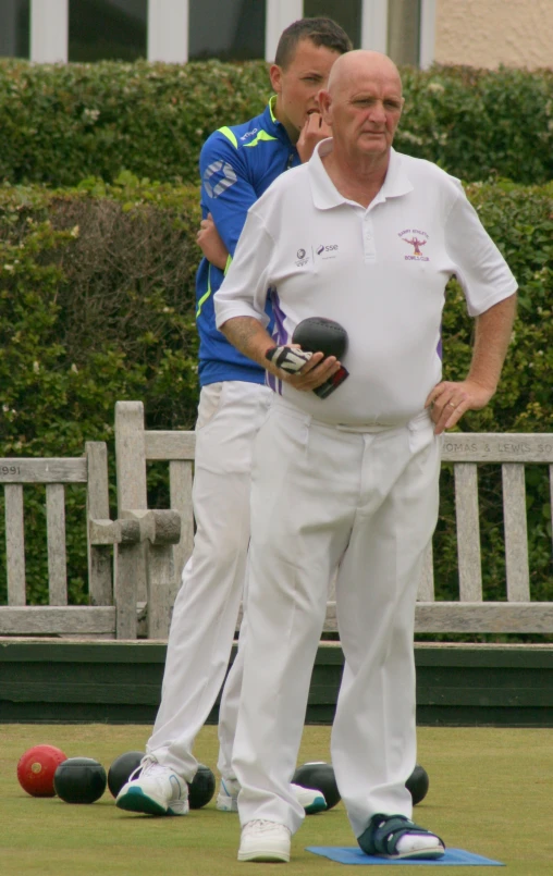 two older men standing near each other playing bowls