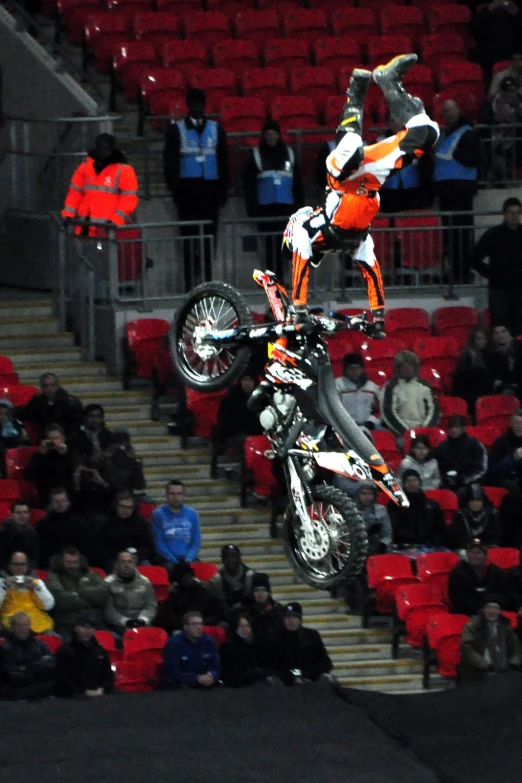 a person on a motorcycle is jumping in the air over an auditorium