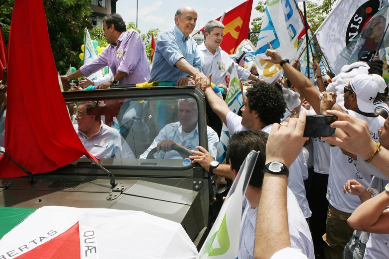 a truck full of people waving flags and shaking hands