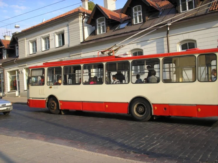 a red and beige city bus on street next to buildings