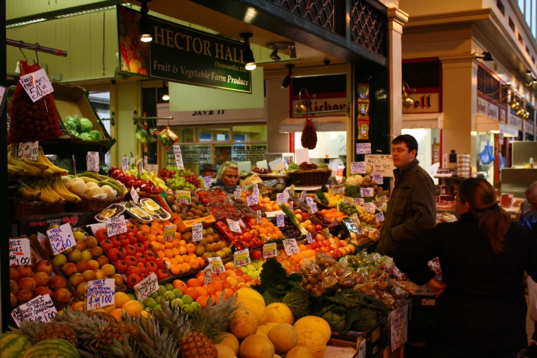 an indoor fruit stand with people buying fruits