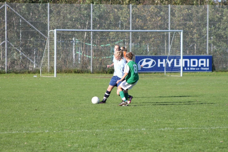 children in green and white uniforms playing soccer on a grassy field
