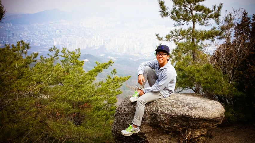 a man sitting on a rock near trees and mountains