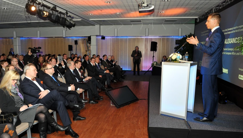 a man giving a speech with people seated in front