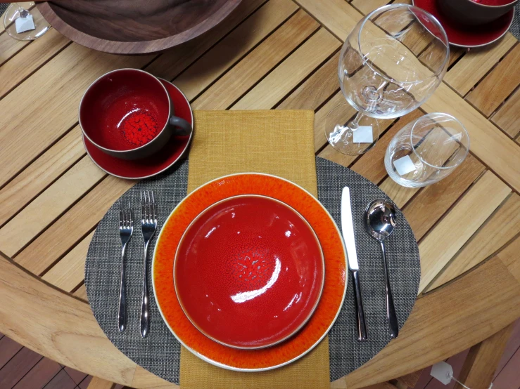 a table set with a bowl, glassware and cloths