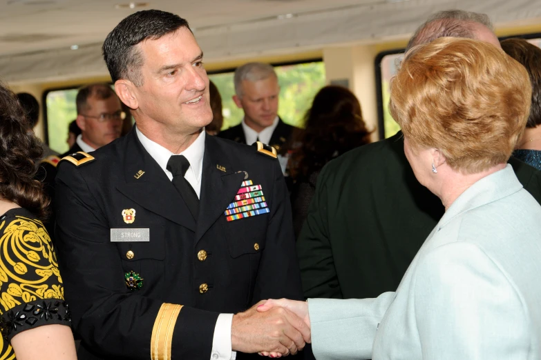 a man in military uniform shakes hands with a woman