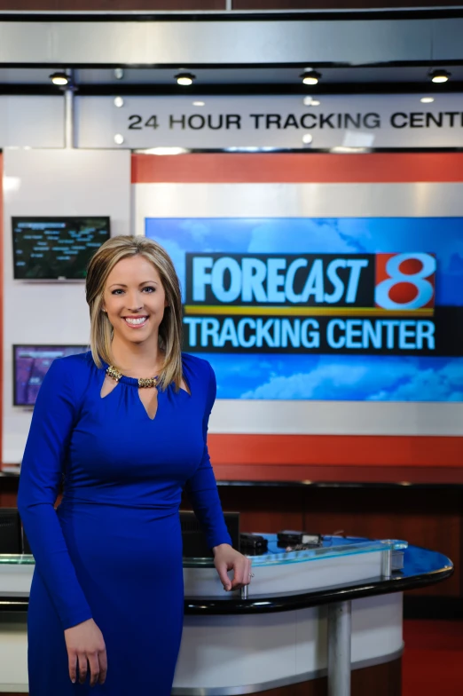 a news anchor posing in front of a news desk