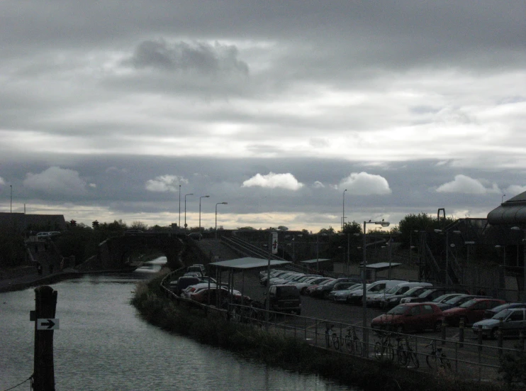 a parking lot next to the water with many parked cars in it