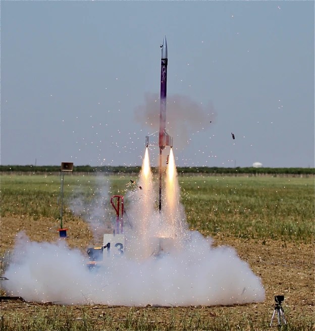 smoke billows from a rocket in an open field