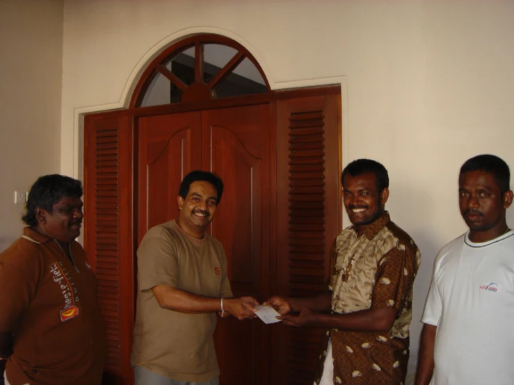 three men standing in front of a door shaking hands