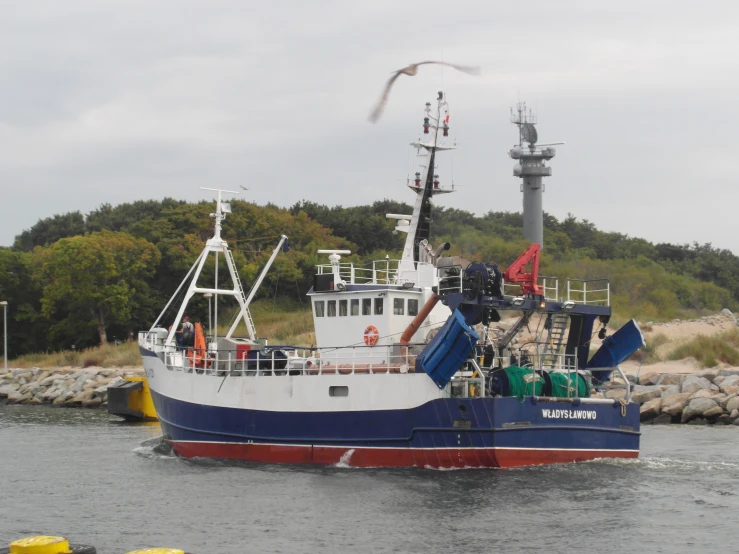 a fishing vessel floating on top of water near the shore